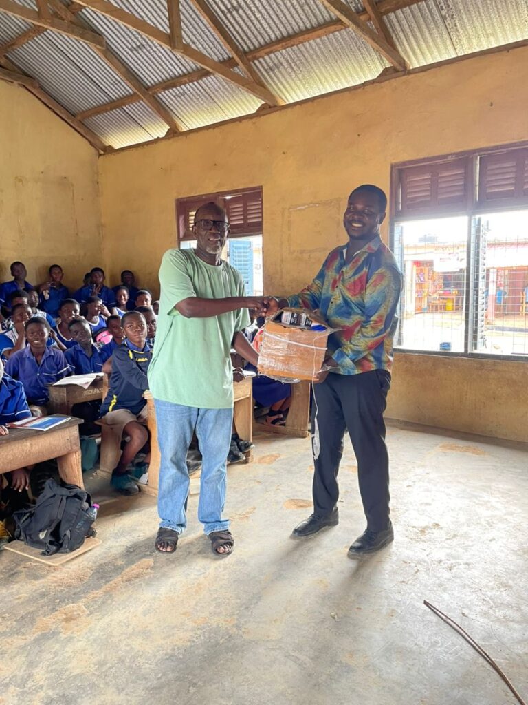 Presby Basic A JHS, Oliver given a set of books and pens to Emmanuel the teacher leader of the club.